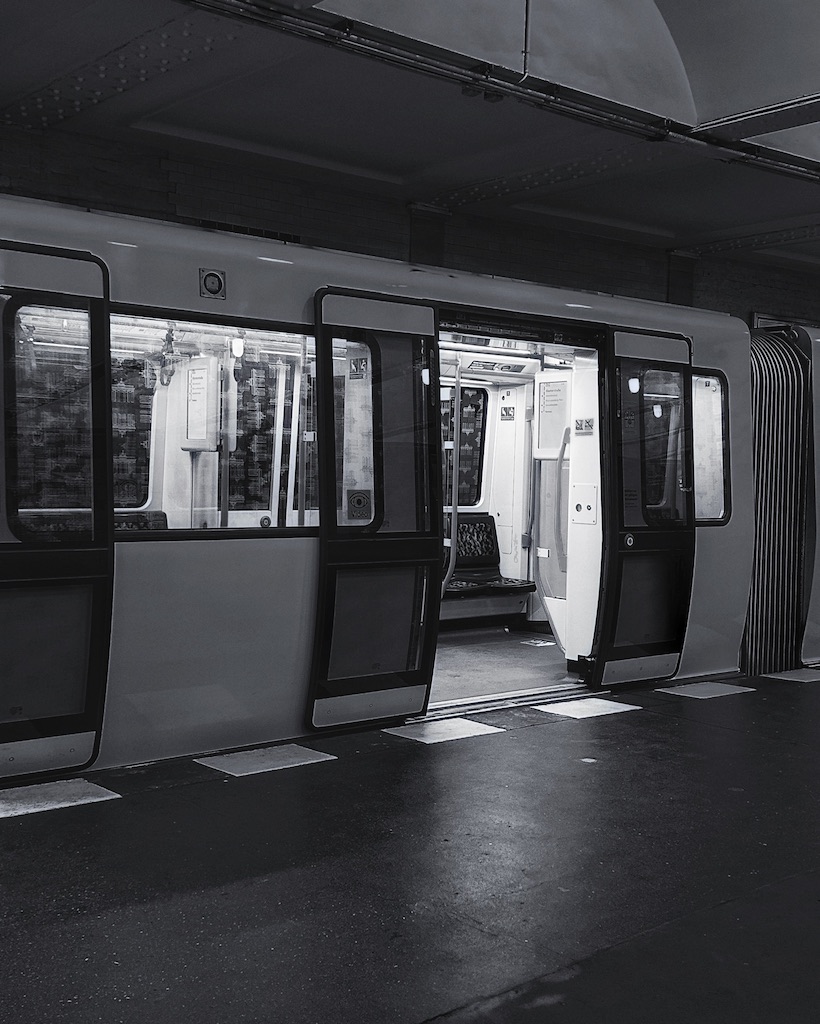 Black and white photo of a metro train carriage with open doors on an empty platform.